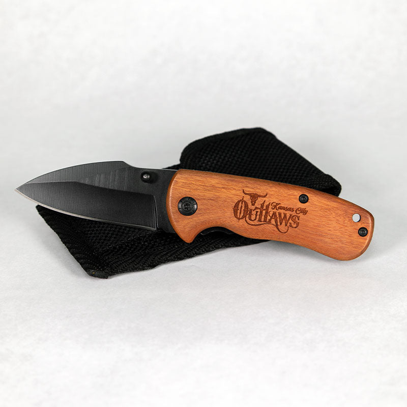 Folding knife with wooden handle and black blade on a white background
